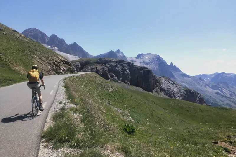 Cycliste sur une route d'altitude face aux sommets du Pays de la Meije